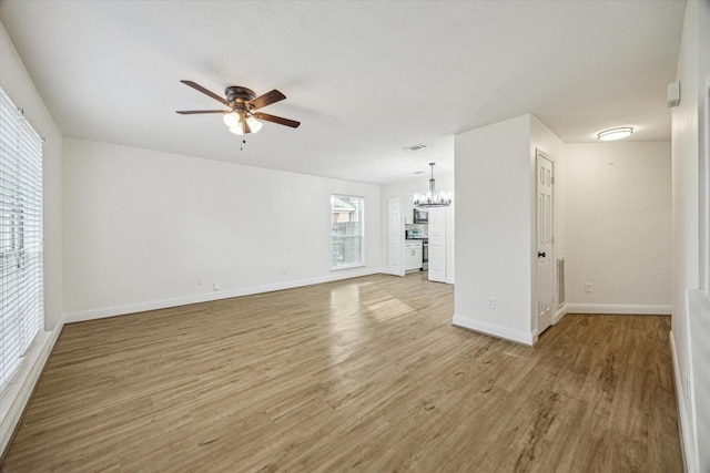 unfurnished living room with visible vents, ceiling fan with notable chandelier, baseboards, and light wood finished floors