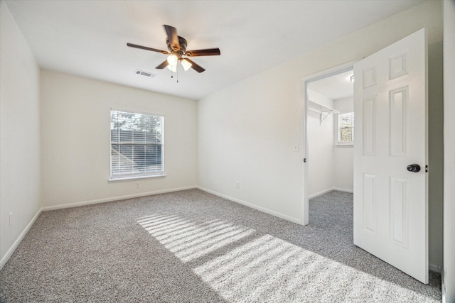 carpeted empty room featuring visible vents, baseboards, and a ceiling fan