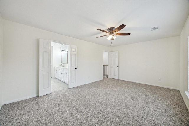 unfurnished bedroom featuring a ceiling fan, visible vents, baseboards, light colored carpet, and connected bathroom