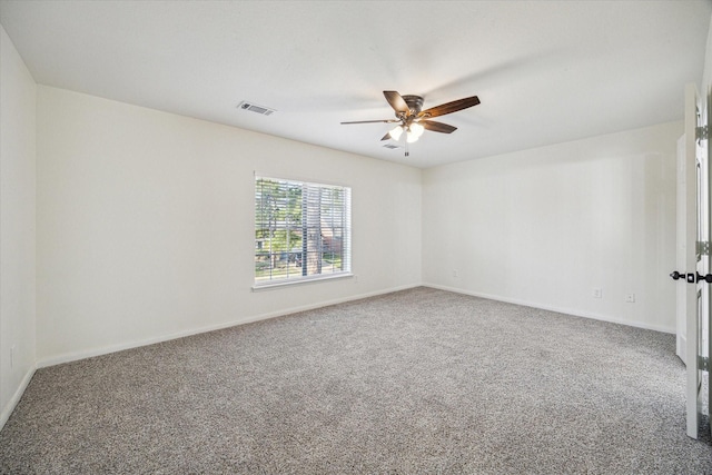 spare room with carpet flooring, a ceiling fan, visible vents, and baseboards