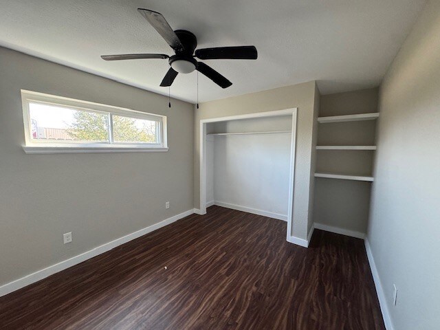 4706 Yellowstone Blvd, Houston, TX 77021 - unfurnished bedroom featuring dark wood-style floors, ceiling fan, a closet, and baseboards