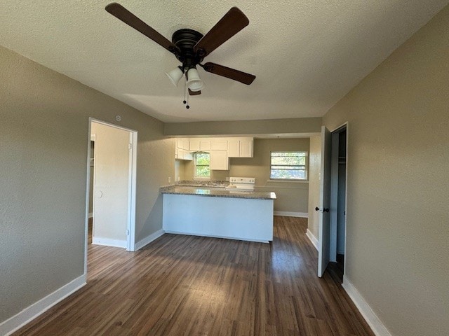 4706 Yellowstone Blvd, Houston, TX 77021 - kitchen featuring a peninsula, dark wood-style floors, white cabinets, a ceiling fan, and range