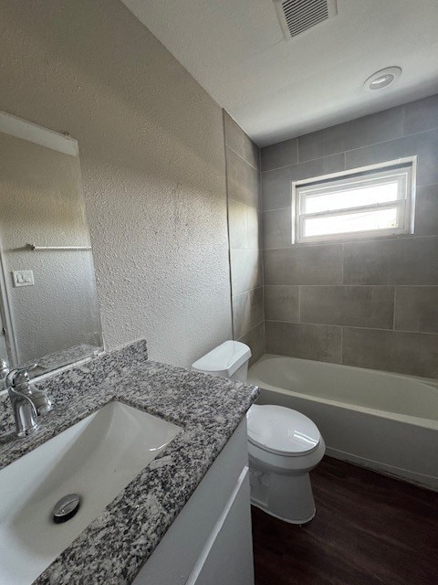 4706 Yellowstone Blvd, Houston, TX 77021 - full bathroom with visible vents, toilet, a textured wall, and wood finished floors