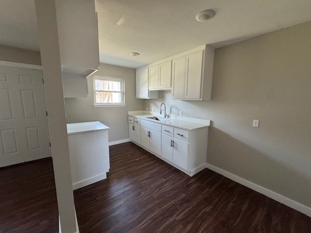 4706 Yellowstone Blvd, Houston, TX 77021 - kitchen featuring dark wood-style floors, baseboards, a sink, white cabinets, and a textured ceiling