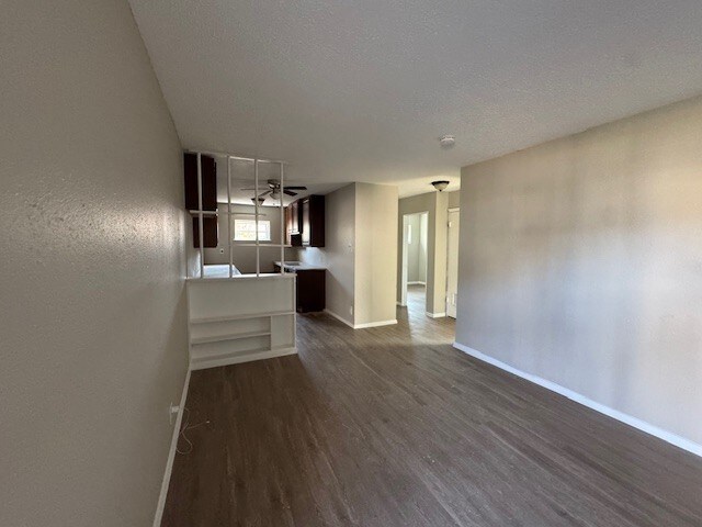 4706 Yellowstone Blvd, Houston, TX 77021 - unfurnished living room featuring baseboards, a textured ceiling, and dark wood finished floors