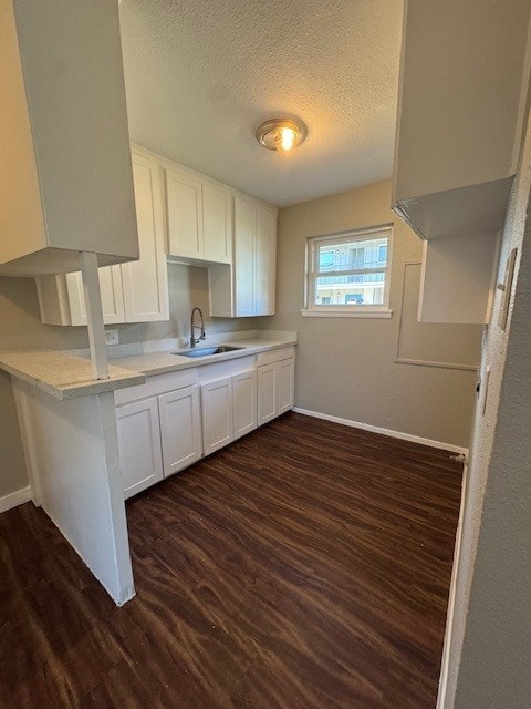 4706 Yellowstone Blvd, Houston, TX 77021 - kitchen with a sink, a textured ceiling, dark wood finished floors, white cabinetry, and light countertops