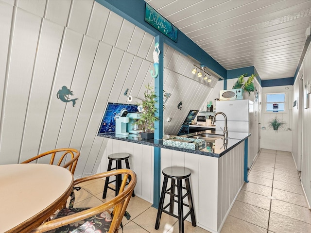 109 Beach Dr, Surfside Beach, TX 77541 - kitchen featuring a sink, freestanding refrigerator, dark stone counters, a peninsula, and a breakfast bar area