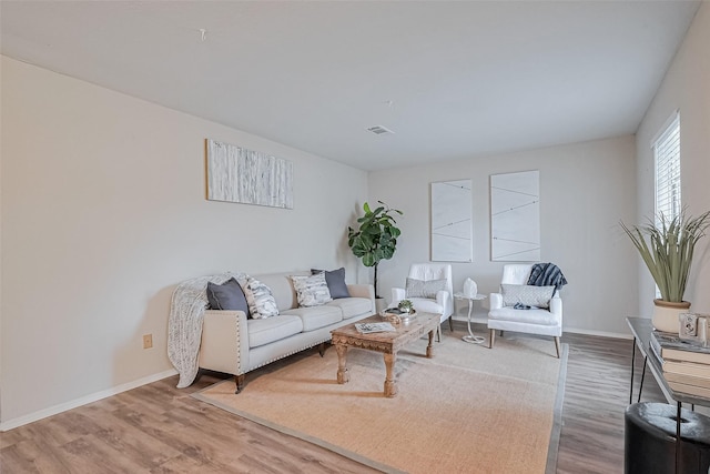 living area with wood finished floors, baseboards, and visible vents