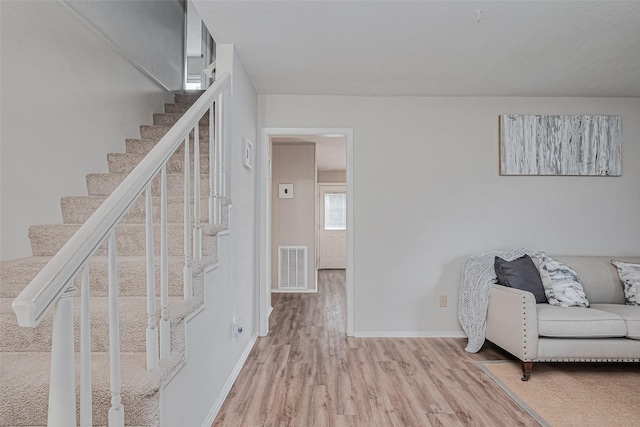 interior space featuring visible vents, light wood-style flooring, stairway, and baseboards