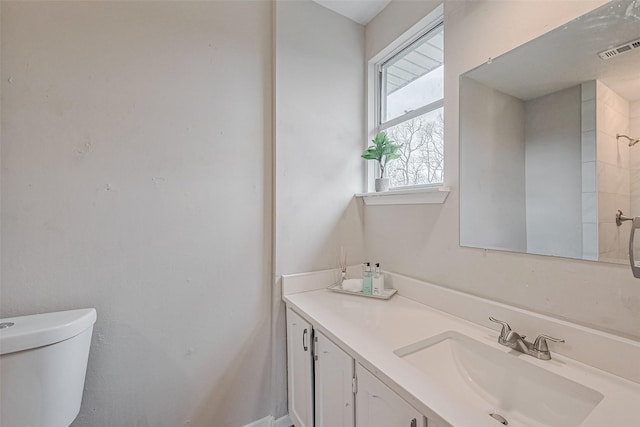 bathroom with toilet, vanity, and visible vents