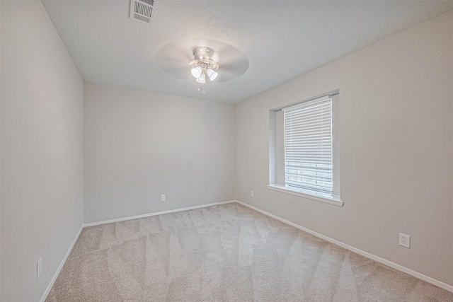 carpeted spare room featuring visible vents, ceiling fan, and baseboards
