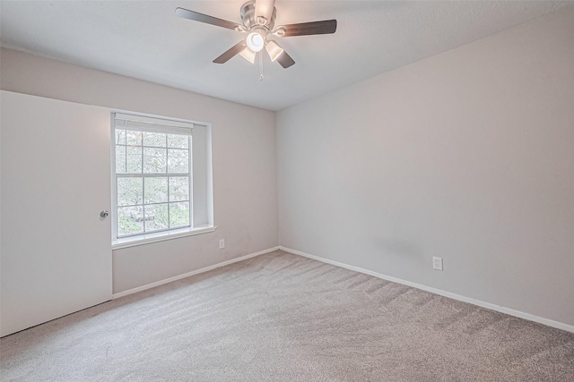 carpeted spare room with baseboards and a ceiling fan