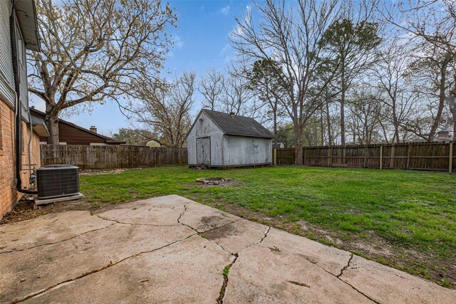 view of yard featuring central AC unit, a storage shed, a fenced backyard, a patio, and an outbuilding