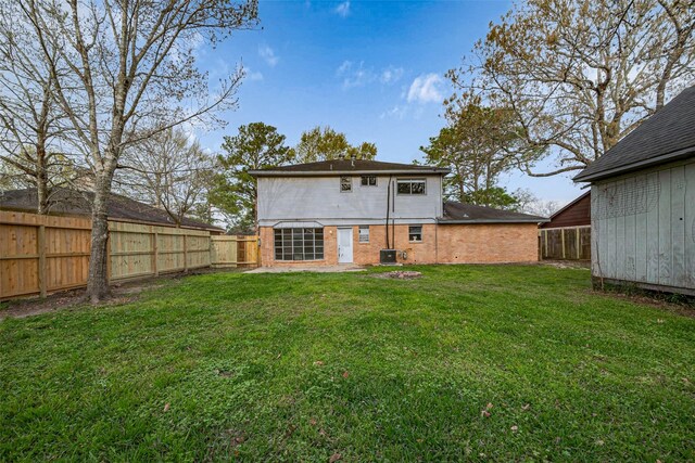 back of property with a yard, a fenced backyard, and brick siding