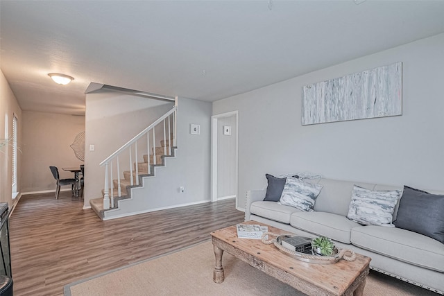 living room featuring baseboards, wood finished floors, and stairs