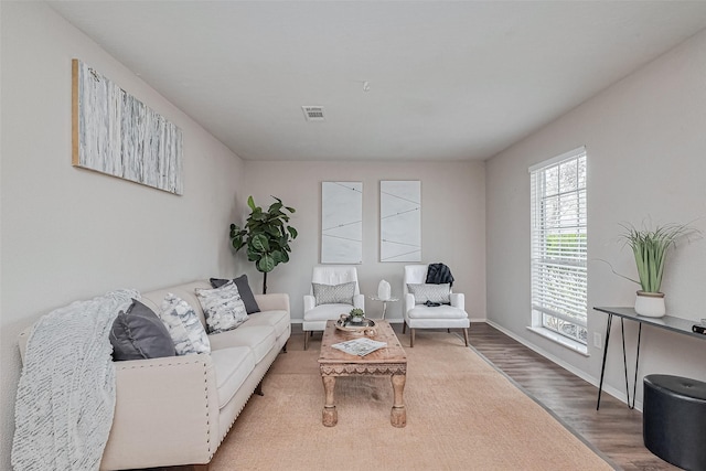 living area with wood finished floors, baseboards, and visible vents