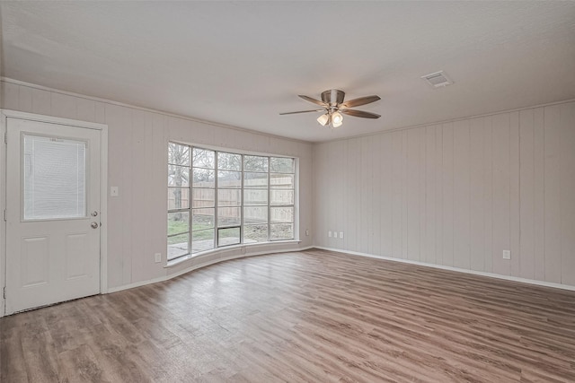 unfurnished living room with wood finished floors, ceiling fan, baseboards, and visible vents