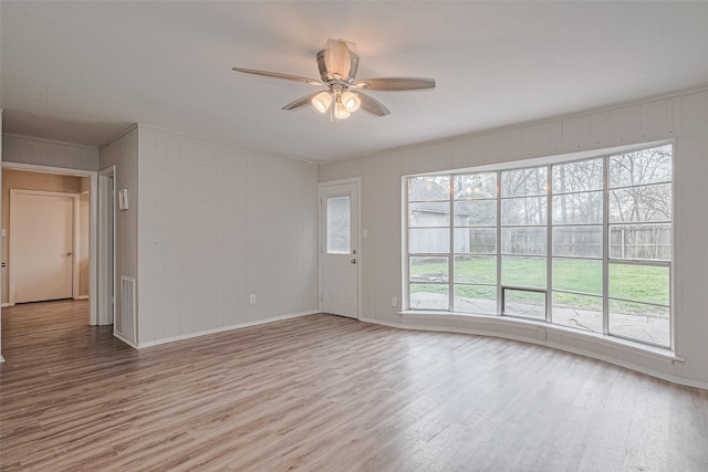 empty room featuring wood finished floors, ceiling fan, baseboards, and plenty of natural light