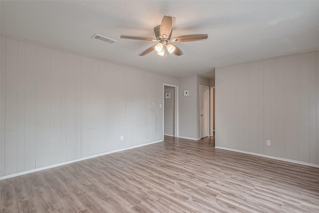 spare room featuring wood finished floors, baseboards, a ceiling fan, and visible vents
