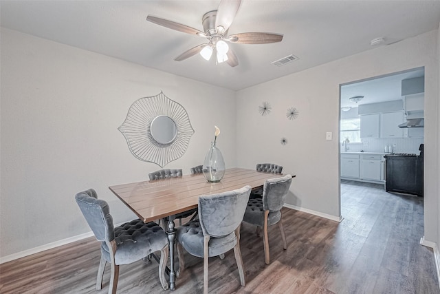 dining room featuring wood finished floors, baseboards, a ceiling fan, and visible vents