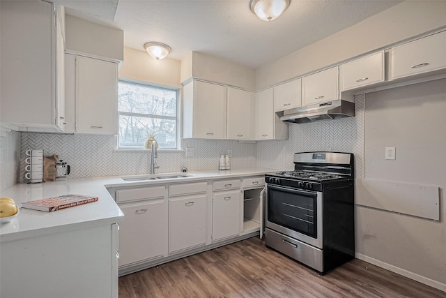 kitchen with light countertops, stainless steel gas range oven, under cabinet range hood, a sink, and wood finished floors