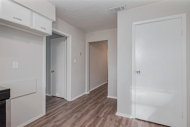 kitchen featuring visible vents, white cabinetry, baseboards, and wood finished floors