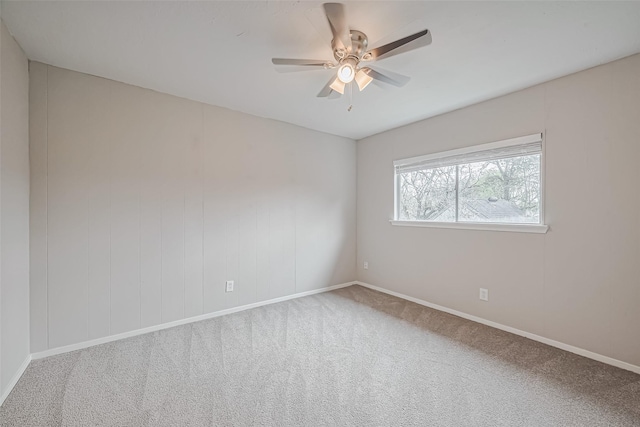 carpeted spare room featuring baseboards and a ceiling fan