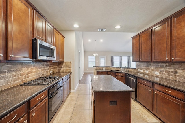 kitchen with a center island, light tile patterned floors, decorative backsplash, stainless steel appliances, and a sink