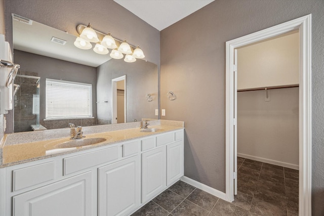 full bathroom with a sink, visible vents, a spacious closet, and a shower stall