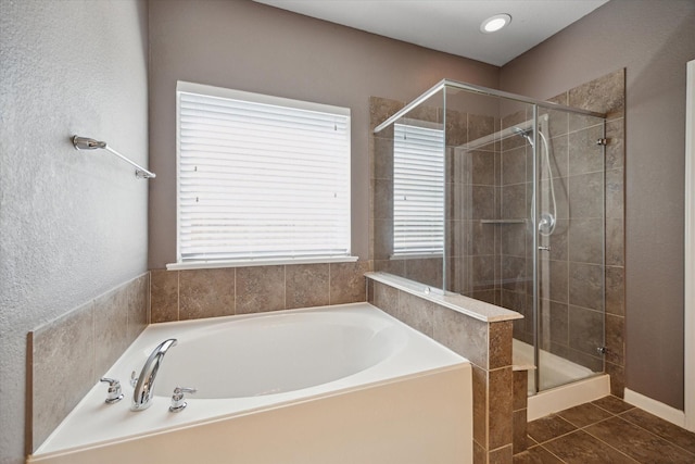 bathroom featuring tile patterned flooring, a shower stall, and a bath