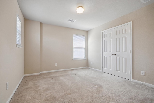 unfurnished bedroom featuring carpet flooring, baseboards, visible vents, and a closet