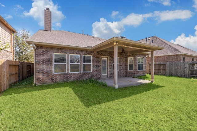 back of property with brick siding, a lawn, a chimney, a fenced backyard, and a patio