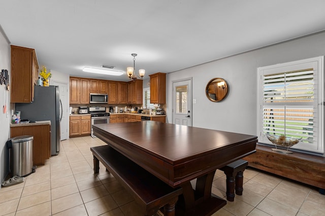 kitchen featuring visible vents, an inviting chandelier, light tile patterned flooring, brown cabinetry, and stainless steel appliances