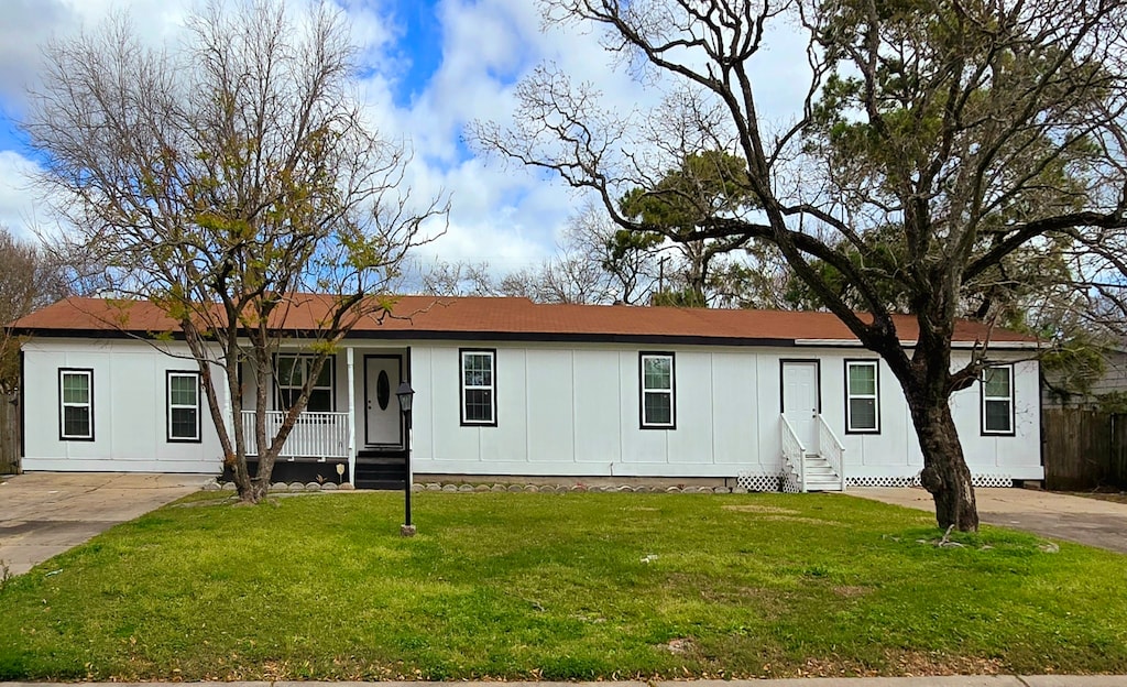 manufactured / mobile home featuring covered porch, board and batten siding, and a front lawn