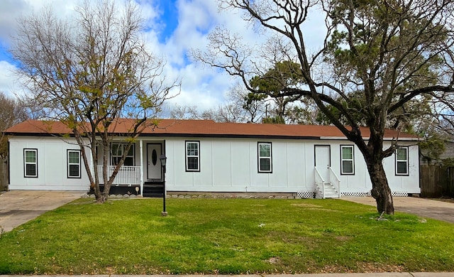 manufactured / mobile home featuring covered porch, board and batten siding, and a front lawn