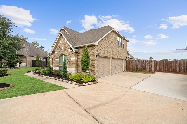 view of property exterior with fence, driveway, brick siding, an attached garage, and a yard