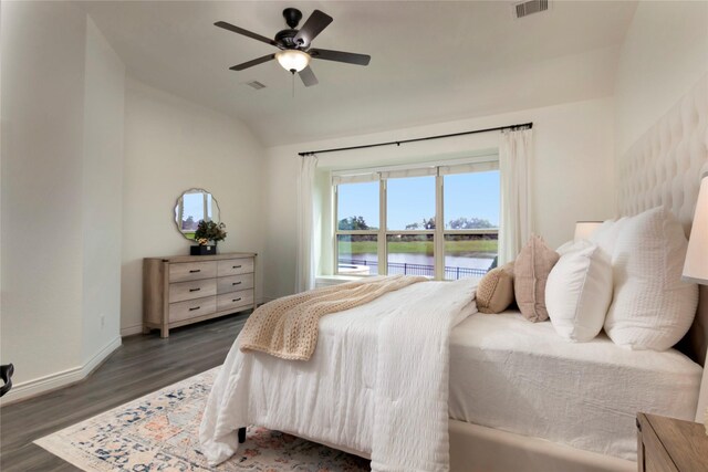 bedroom with a water view, vaulted ceiling, wood finished floors, and visible vents