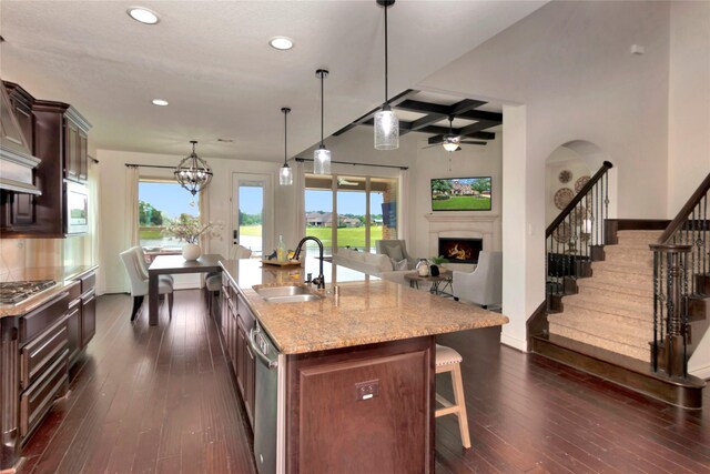 kitchen with a lit fireplace, a kitchen bar, a sink, stainless steel appliances, and recessed lighting