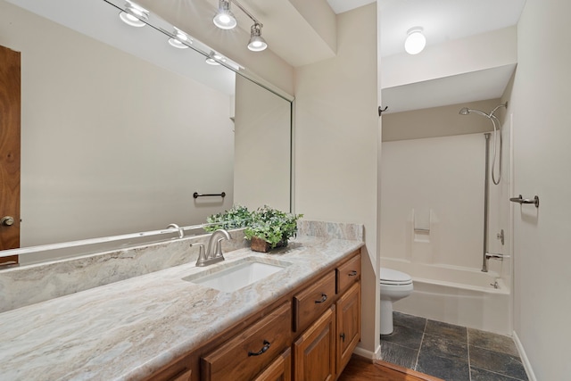 full bathroom featuring baseboards, toilet, stone finish floor, vanity, and  shower combination