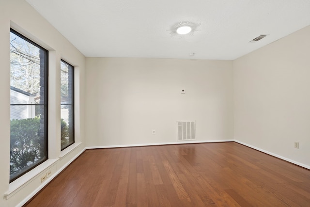 spare room featuring visible vents, baseboards, and wood finished floors