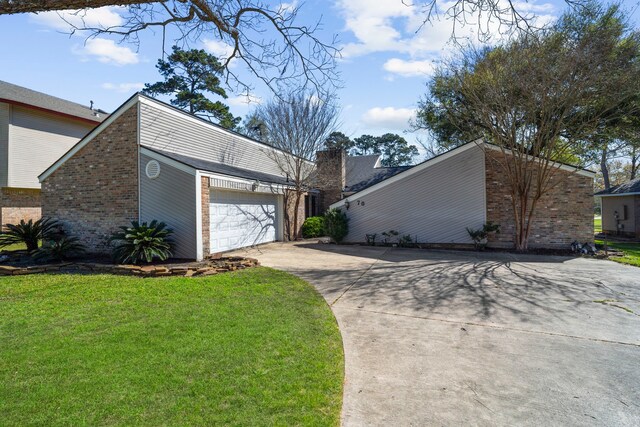 view of side of home with a yard, a chimney, concrete driveway, a garage, and brick siding