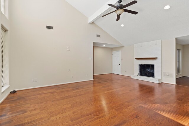 unfurnished living room with wood finished floors, a ceiling fan, visible vents, beam ceiling, and a brick fireplace
