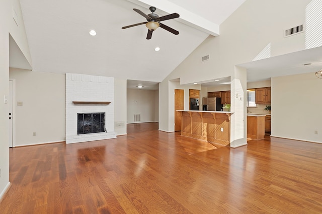 unfurnished living room featuring beamed ceiling, wood finished floors, visible vents, and ceiling fan