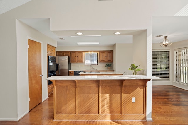 kitchen featuring baseboards, stainless steel fridge with ice dispenser, a breakfast bar area, brown cabinets, and wood finished floors