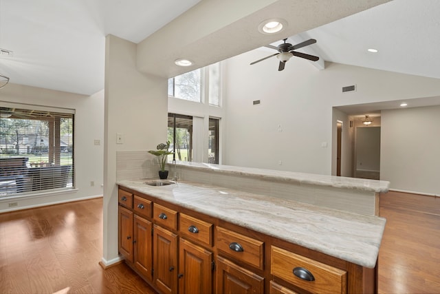 kitchen featuring brown cabinetry, wood finished floors, visible vents, and ceiling fan