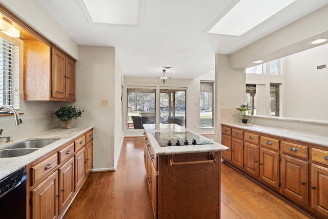 kitchen featuring decorative backsplash, black appliances, wood finished floors, and a sink
