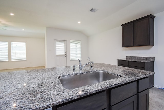 kitchen featuring a sink, visible vents, a healthy amount of sunlight, and dark stone counters