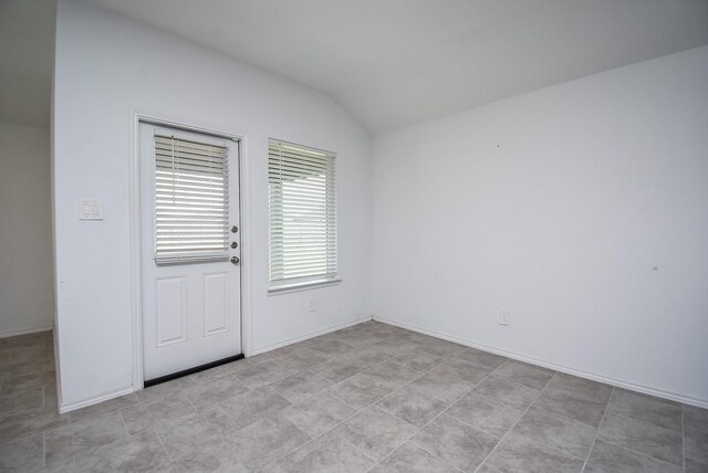 empty room with baseboards and vaulted ceiling