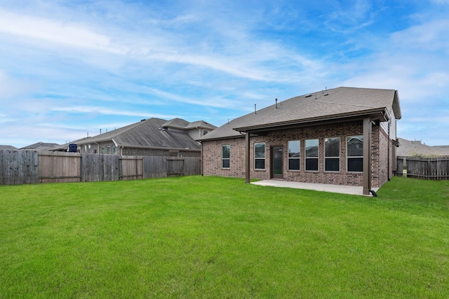 rear view of property with a patio, roof with shingles, a fenced backyard, a lawn, and brick siding