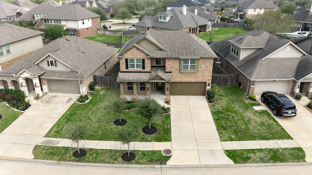 view of front of home with fence, a residential view, concrete driveway, a front yard, and brick siding